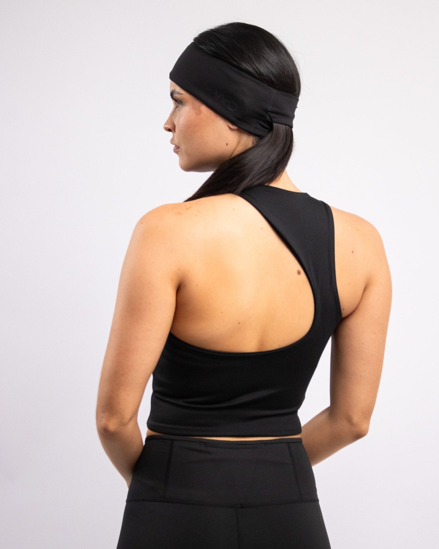 A person wearing a black tank top with an open back design, viewed from the back.