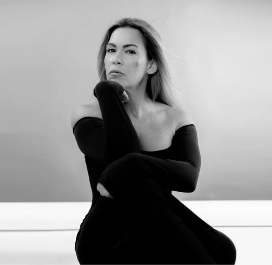 Black and white photo of a woman wearing a black off-shoulder top.